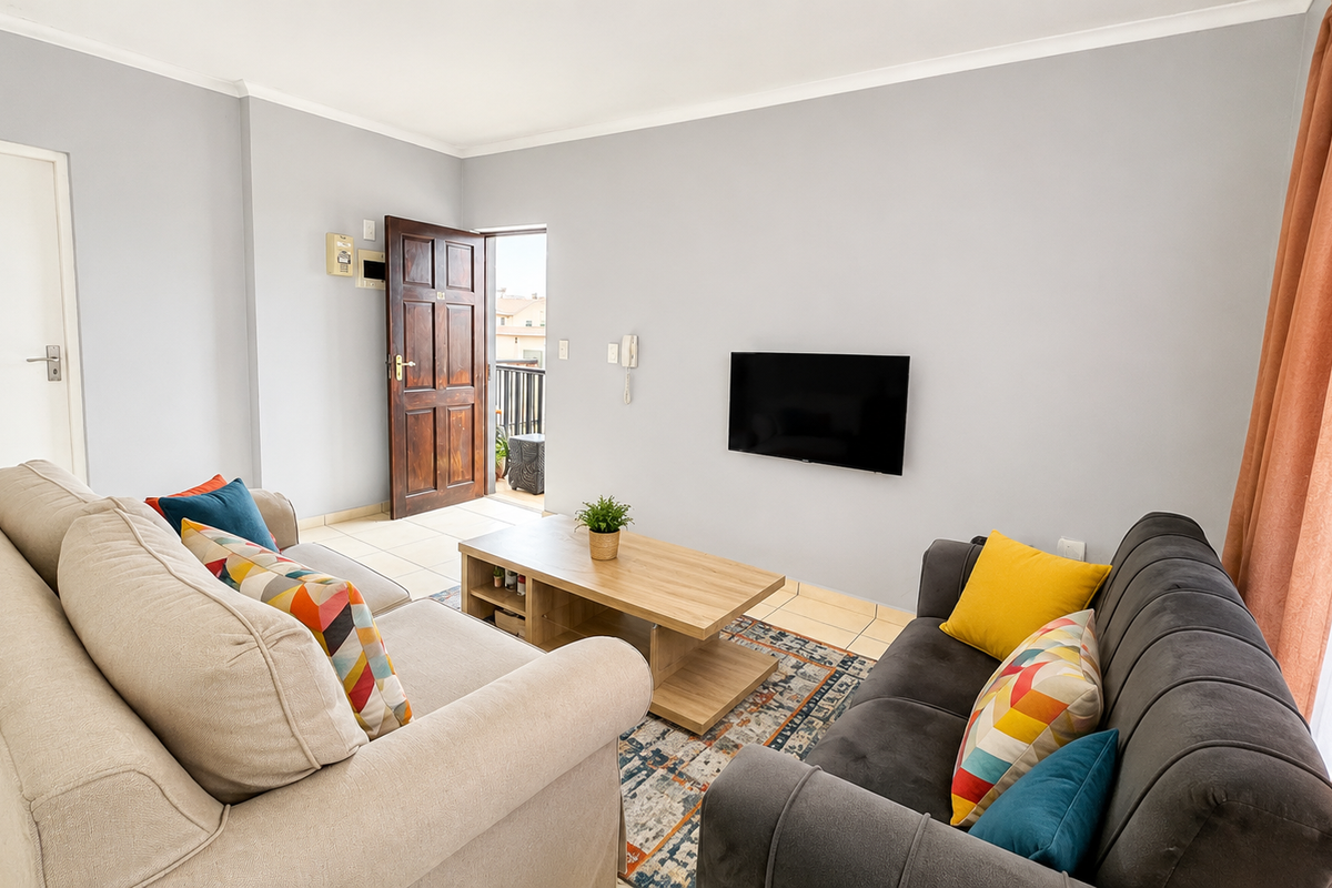 A bright living room featuring tiled flooring, neutral walls, and direct access to an outdoor balcony area.