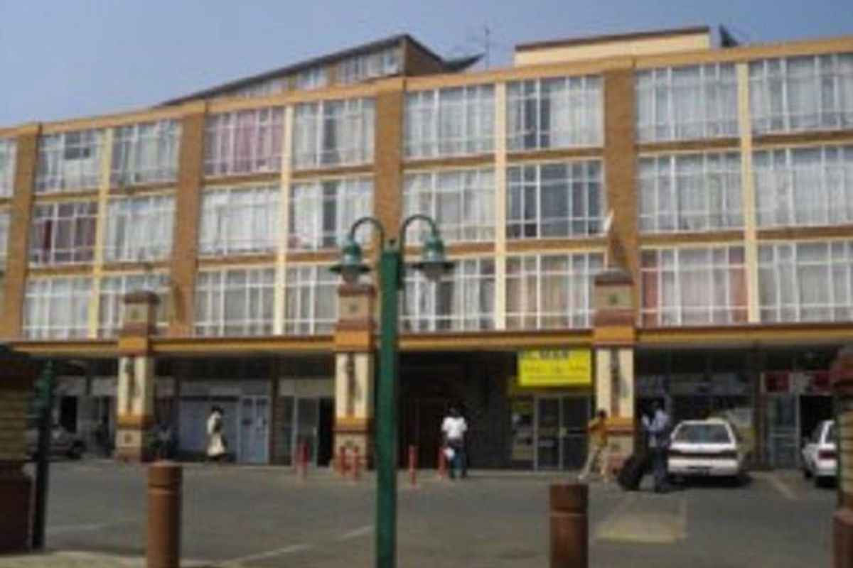 Front elevation of a multi-story commercial building featuring ground-level retail storefronts and large glass windows across the upper levels.