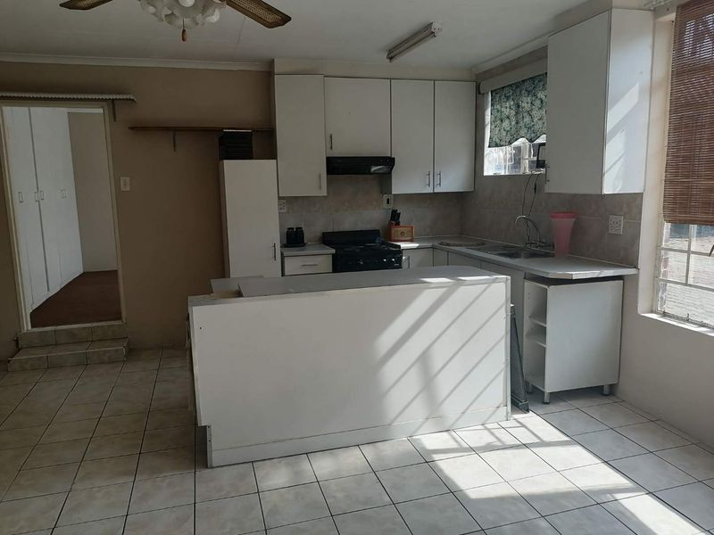 A functional kitchen featuring white cabinetry, a central island, and tiled flooring. The space offers a practical layout with built-in appliances and ample storage.