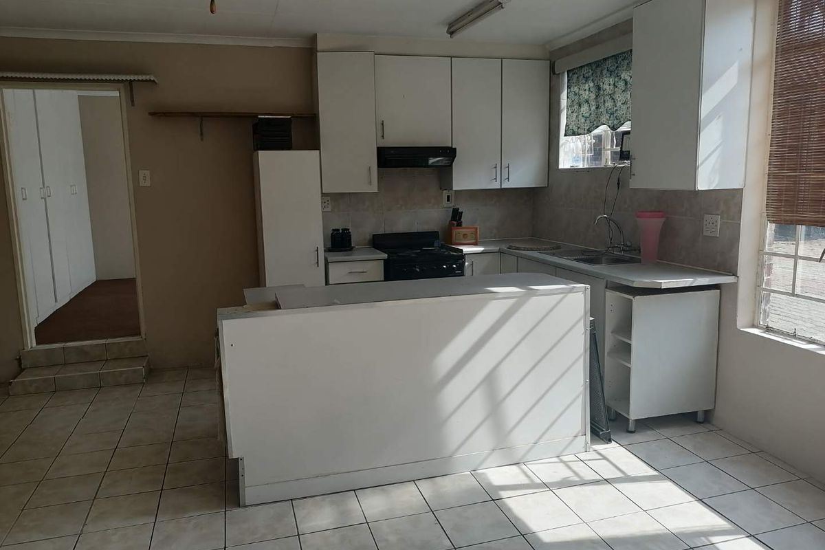A functional kitchen featuring white cabinetry, a central island, and tiled flooring. The space offers a practical layout with built-in appliances and ample storage.