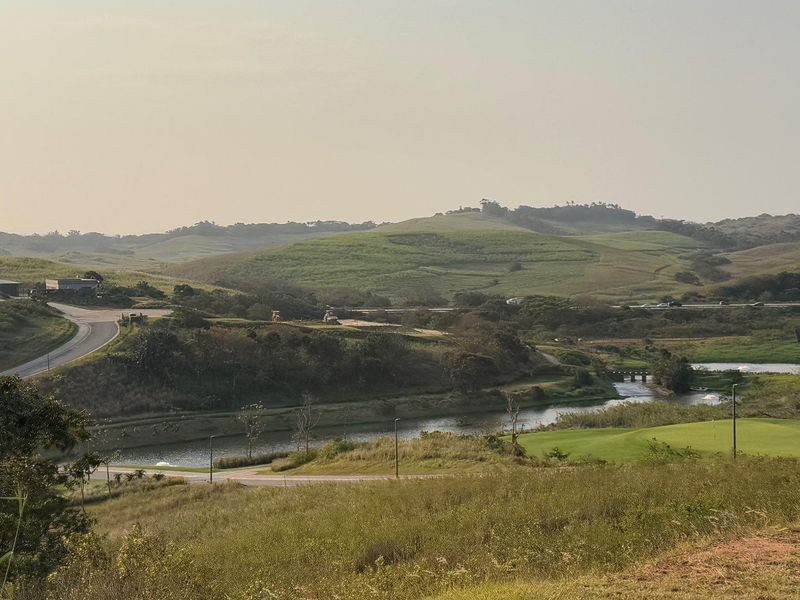 A scenic landscape view overlooking rolling hills, a water body, and surrounding road infrastructure within a residential estate setting.
