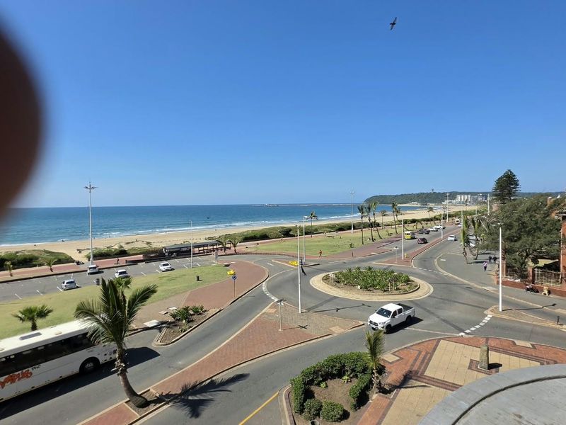 Elevated coastal view overlooking the beach, promenade, and surrounding street infrastructure.