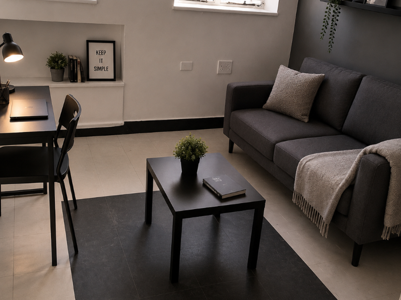 A well-lit living room featuring decorative window security grilles, neutral vinyl tile flooring, and a dark grey accent wall.