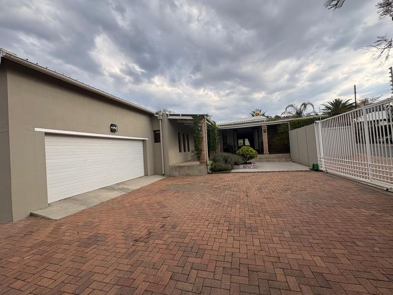 Front exterior view featuring a brick paved driveway, automated garage, and a covered entrance porch with brick detailing.