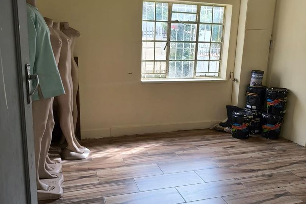A vacant bedroom featuring wood-look tiled flooring, a metal-framed window with security bars, and a textured ceiling.