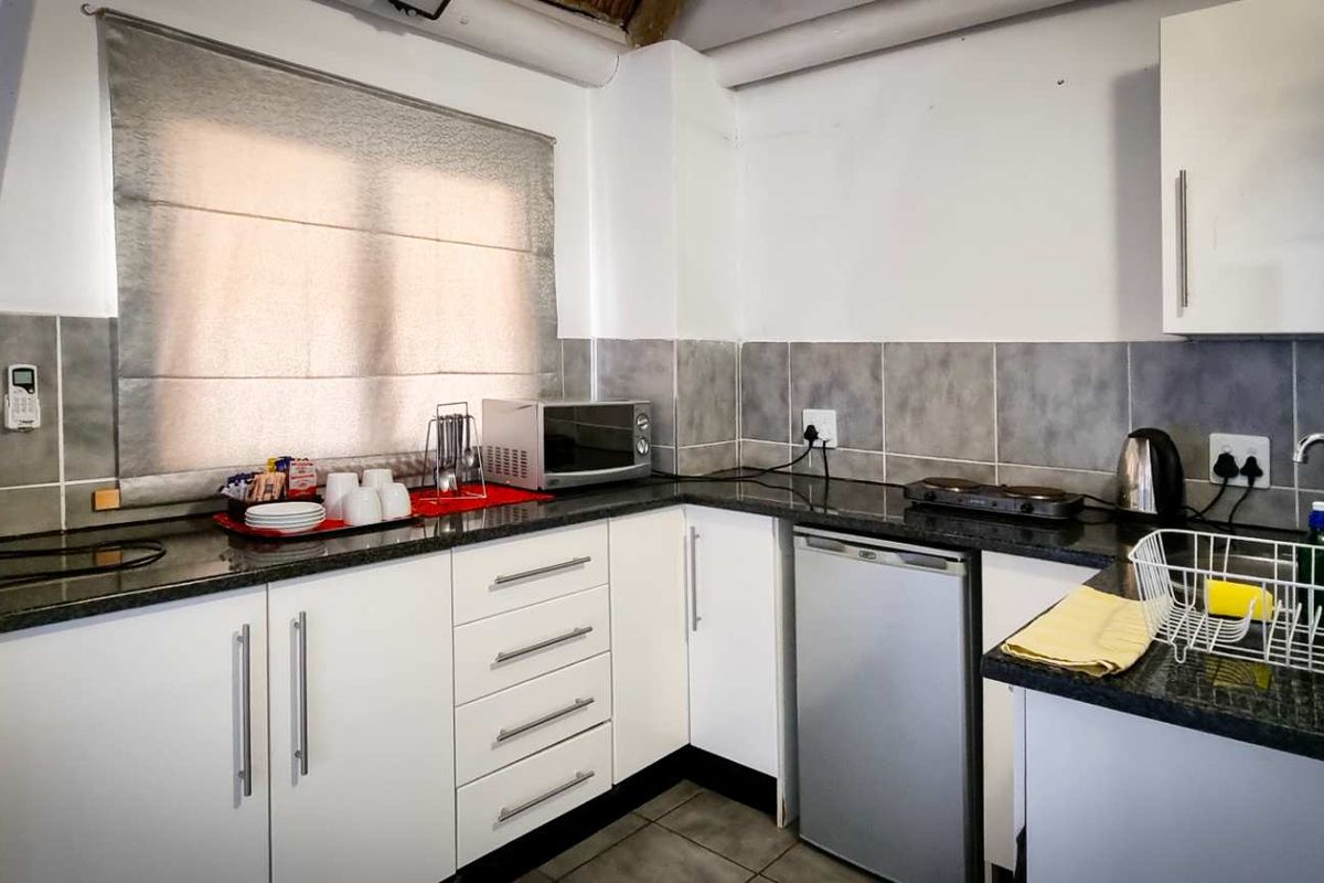 Compact kitchenette featuring white cabinetry, dark granite countertops, tiled backsplash, and integrated sink, suitable for a small business or office space.