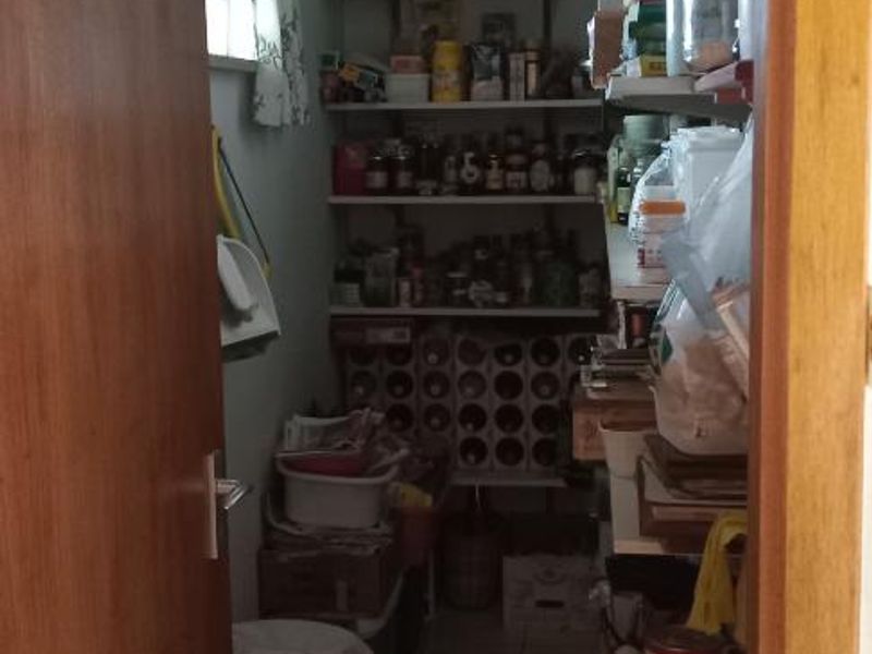 A functional walk-in pantry or scullery area featuring tiled flooring and extensive built-in shelving for storage.