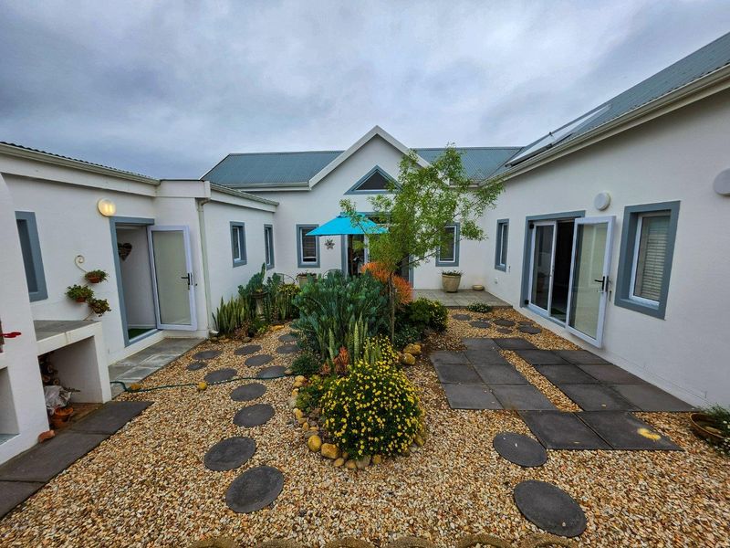 A well-maintained rear courtyard featuring gravel landscaping, stone pathways, and multiple access points to the home through sliding glass doors.
