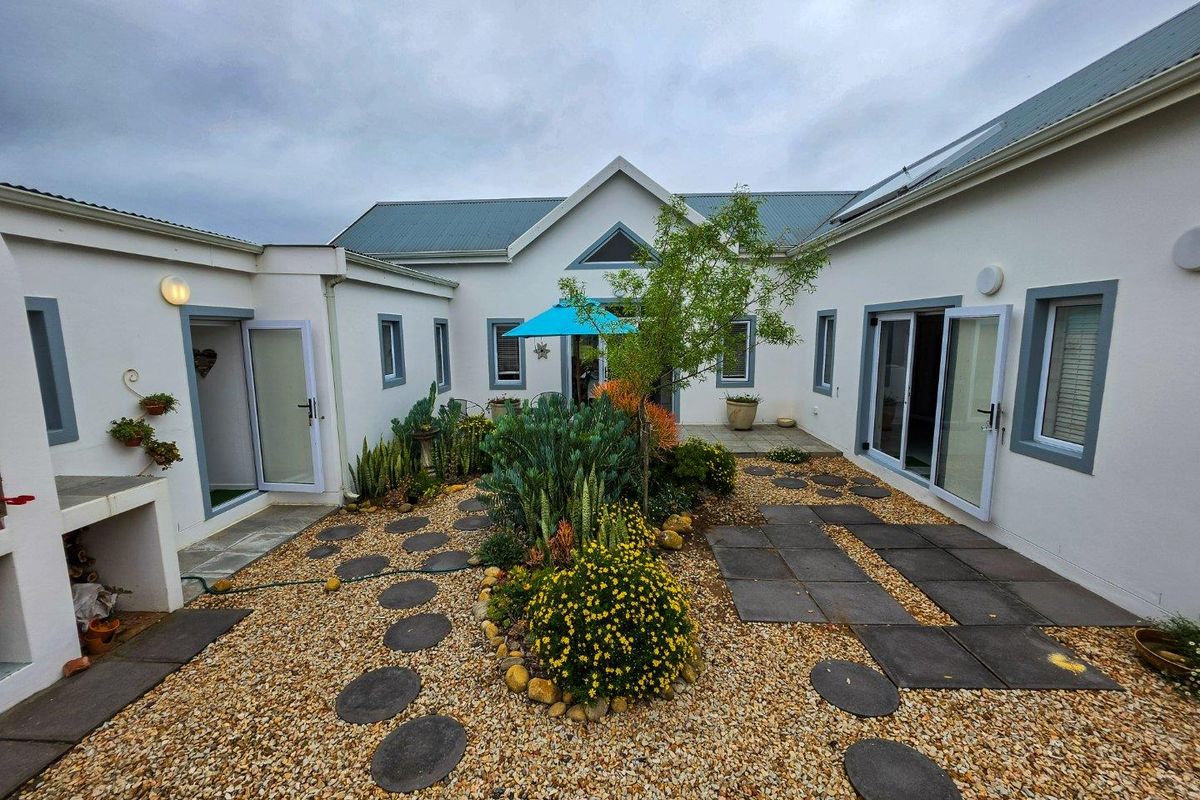 A well-maintained rear courtyard featuring gravel landscaping, stone pathways, and multiple access points to the home through sliding glass doors.