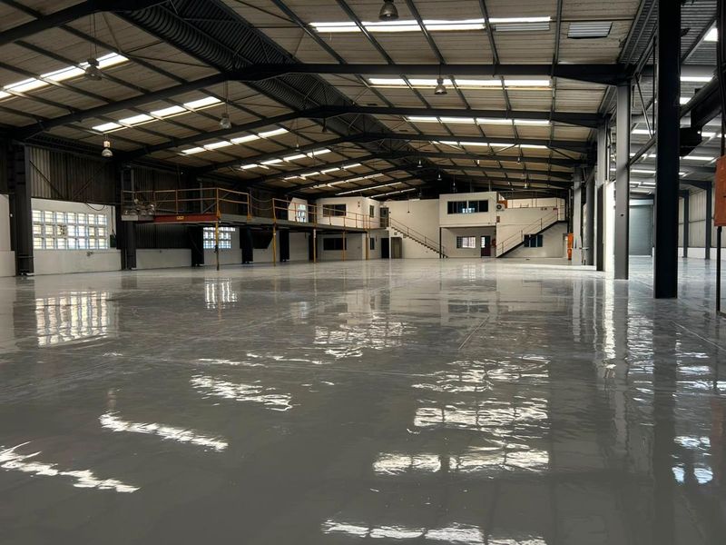 Spacious industrial warehouse featuring a high-gloss epoxy floor, steel portal frame construction, mezzanine level, and ample natural light through integrated skylights.