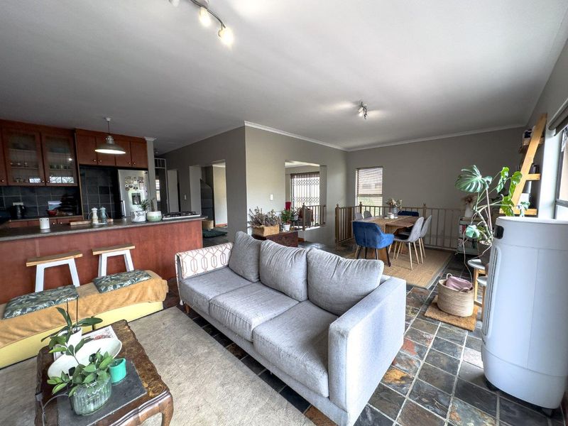 Spacious open-plan living area featuring a kitchen with breakfast counter, dining space, and durable stone tile flooring throughout.