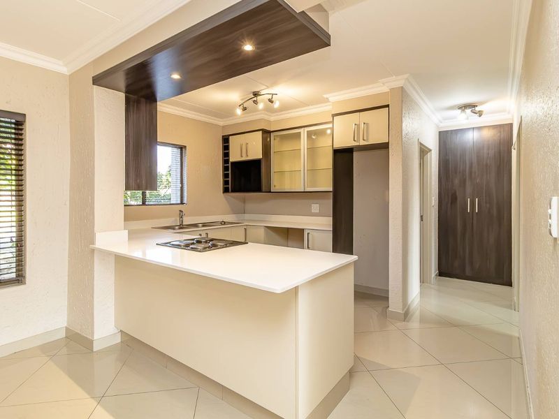 Modern kitchen featuring stone countertops, a gas hob, ample built-in cabinetry, and tiled flooring, offering a clean and functional workspace.