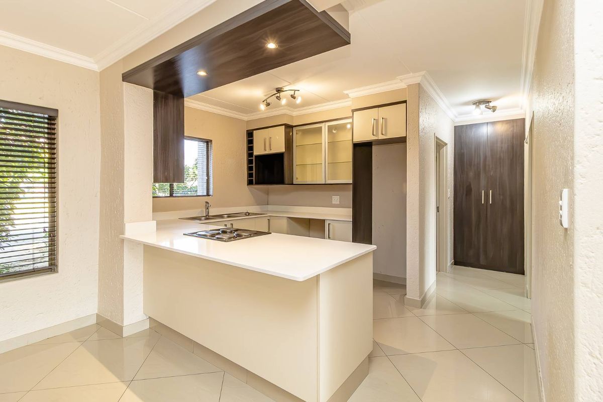 Modern kitchen featuring stone countertops, a gas hob, ample built-in cabinetry, and tiled flooring, offering a clean and functional workspace.