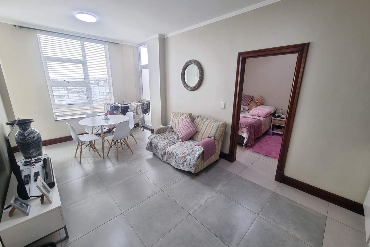 Open plan living area featuring large format floor tiles, neutral wall finishes, and a large window providing natural light.