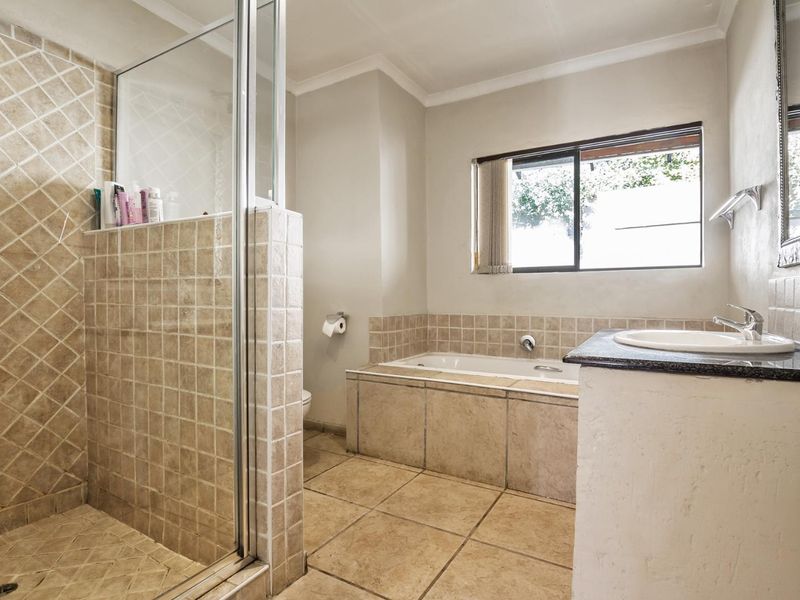 A functional bathroom featuring a tiled shower enclosure, built-in bathtub, and a vanity basin with a granite countertop.