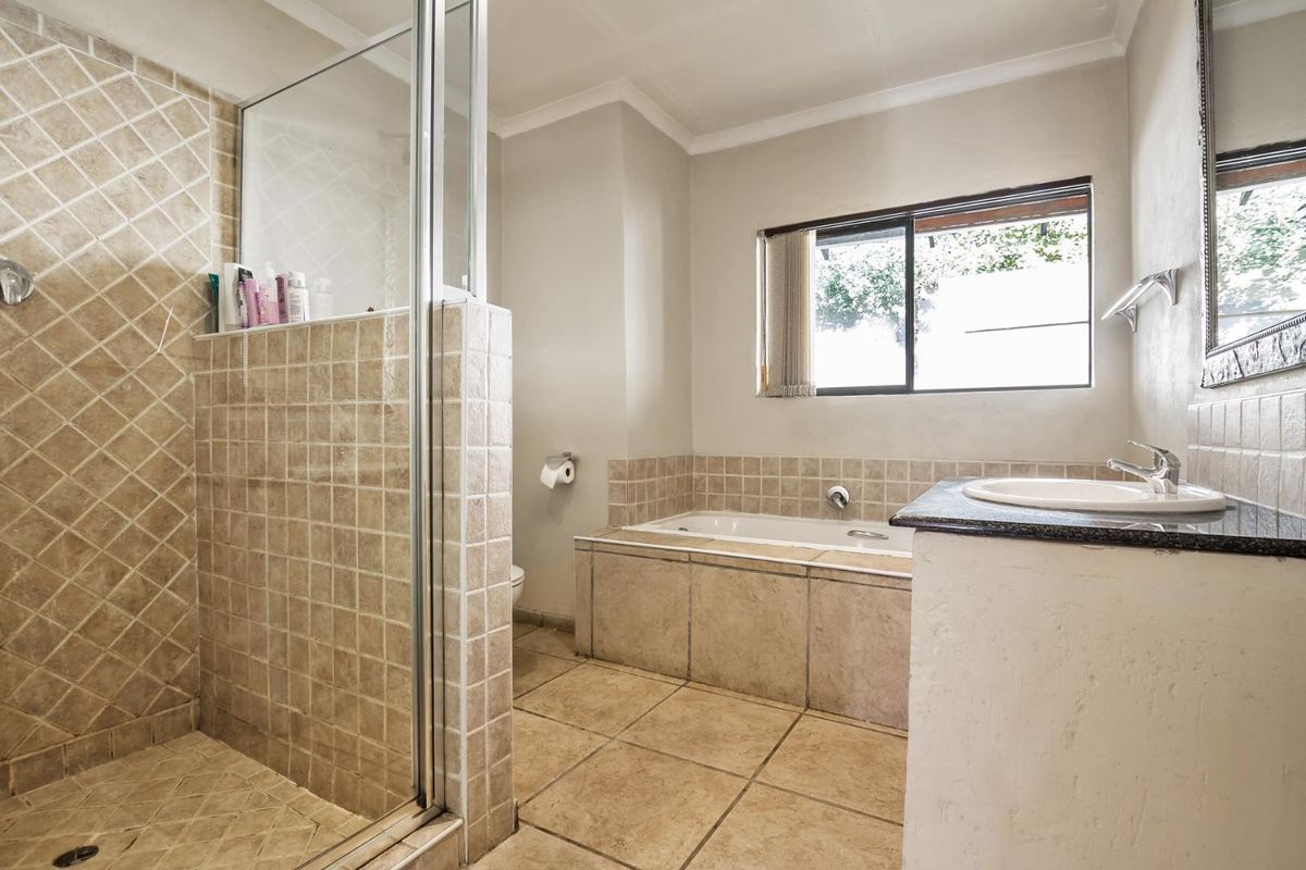 A functional bathroom featuring a tiled shower enclosure, built-in bathtub, and a vanity basin with a granite countertop.