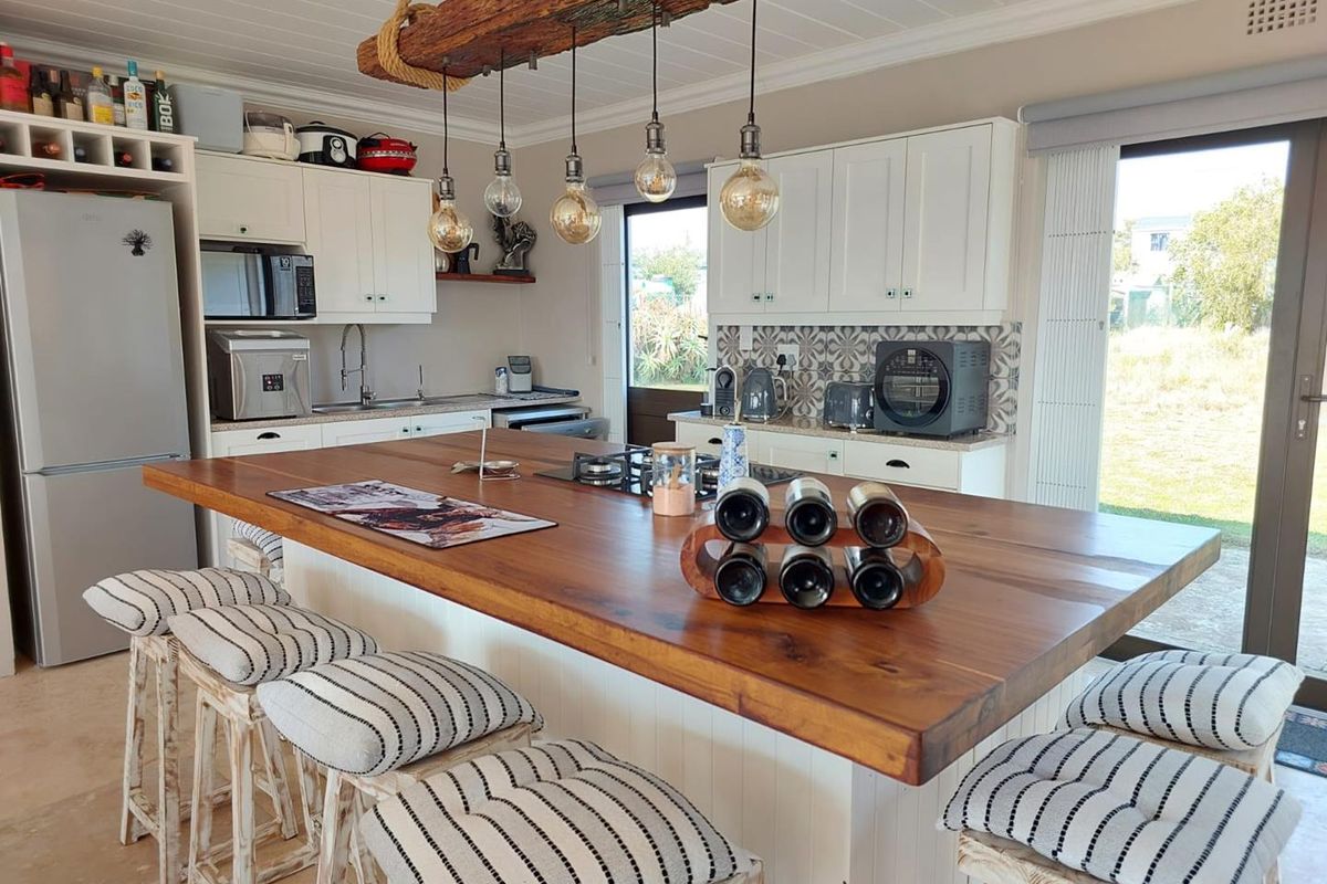 A well-appointed kitchen featuring a large wooden island with a built-in gas hob, shaker-style cabinetry, and a decorative tiled backsplash.