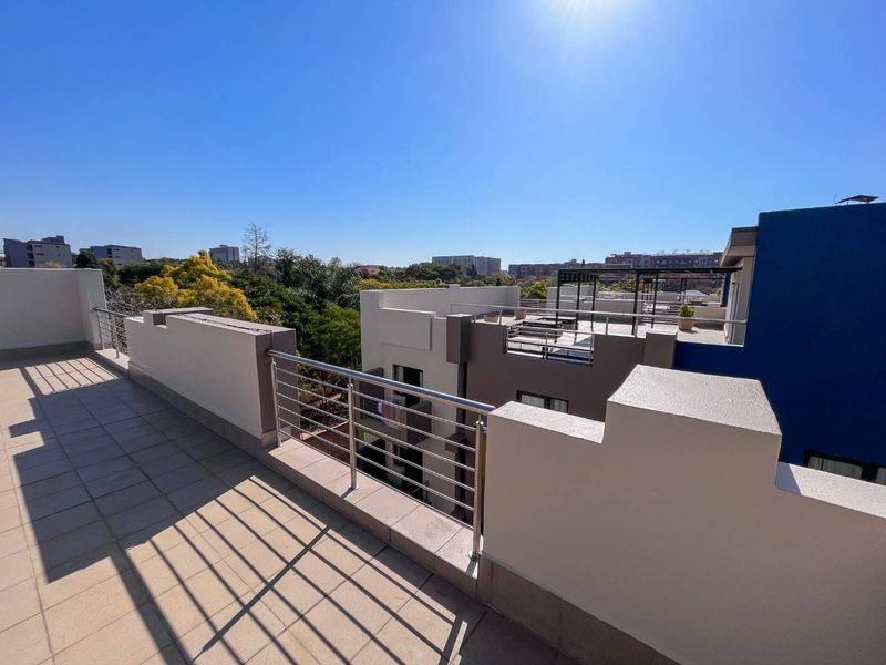 Spacious rooftop balcony featuring tiled flooring and a modern stainless steel balustrade, offering elevated views of the surrounding neighborhood.