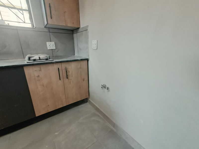 A functional laundry area featuring built-in cabinetry, a laminate countertop, tiled splashback, and dedicated plumbing connections for laundry appliances.