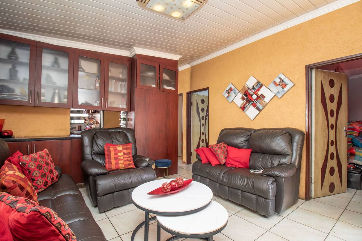 A living room featuring built-in dark wood cabinetry, tiled flooring, and a panelled ceiling with decorative coving.