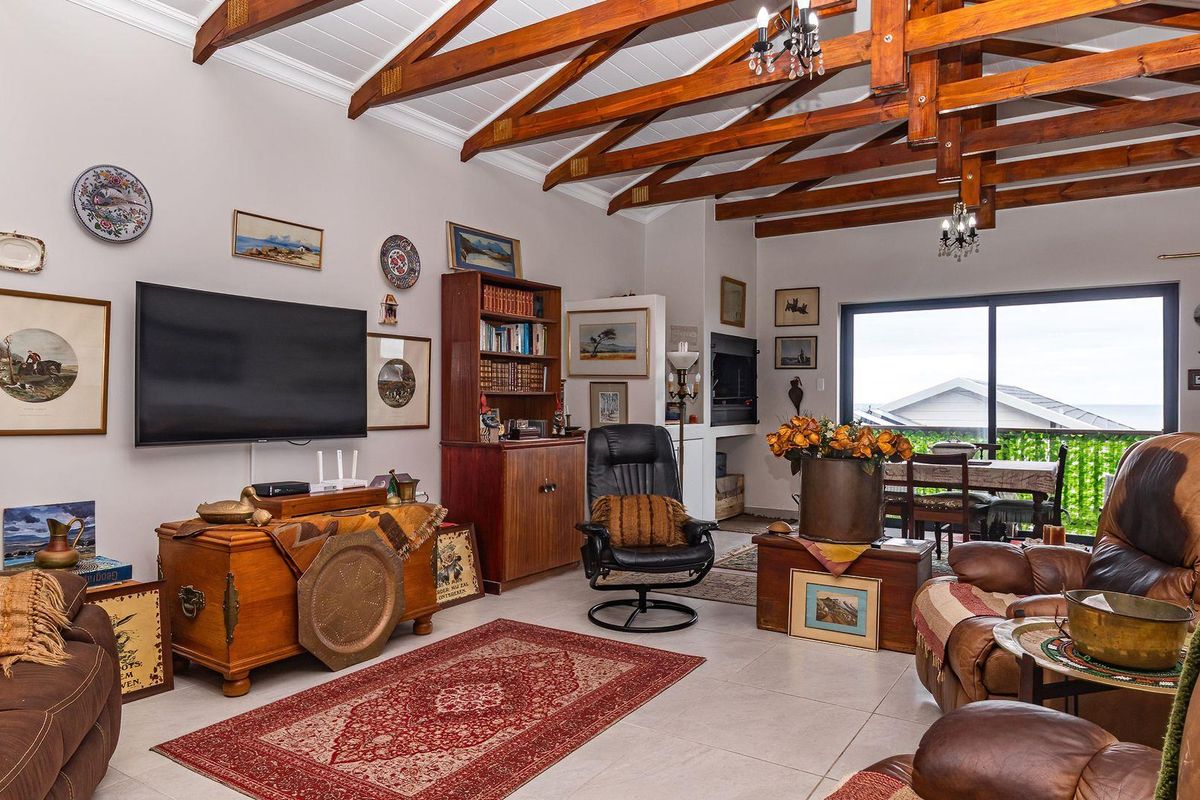 Spacious living area featuring exposed timber roof trusses, tiled flooring, and large sliding glass doors leading to an outdoor balcony.