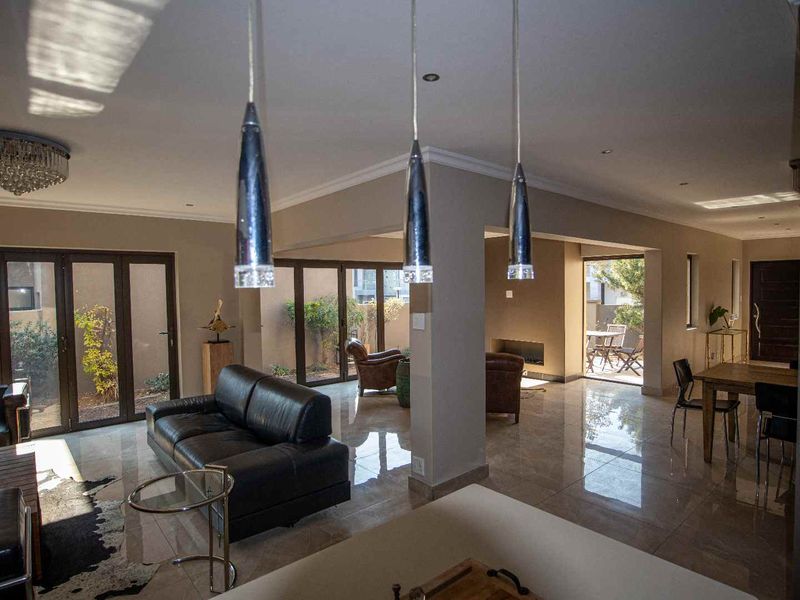 Spacious open-plan living area featuring polished tile flooring, modern pendant lighting, and large sliding glass doors providing seamless access to the outdoor patio.