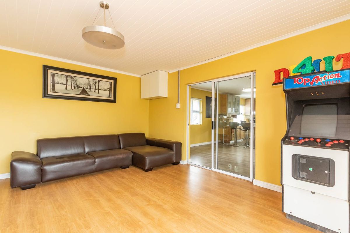 A living area featuring wood-look flooring, tongue-and-groove ceiling, and sliding glass doors providing a view into the adjacent kitchen space.