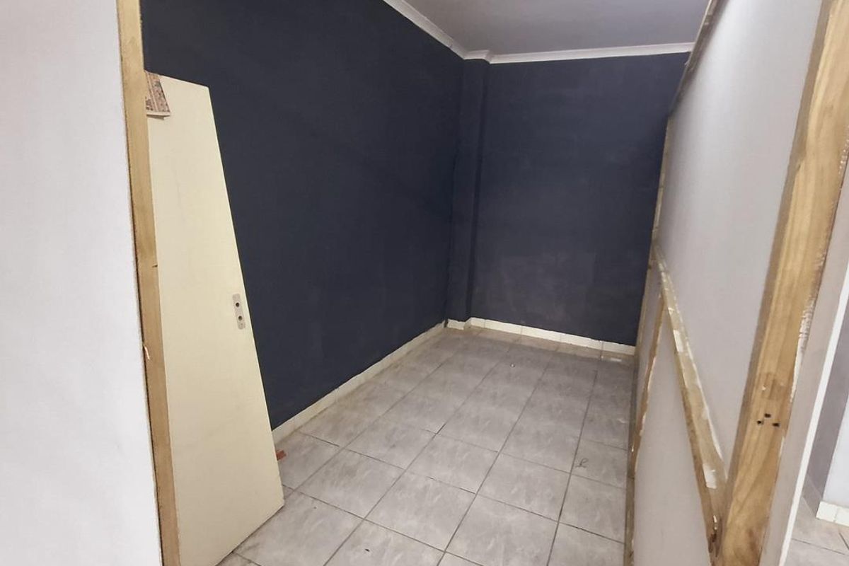 An unfinished interior space featuring tiled flooring and dark accent walls, currently undergoing renovation with exposed timber framing visible.