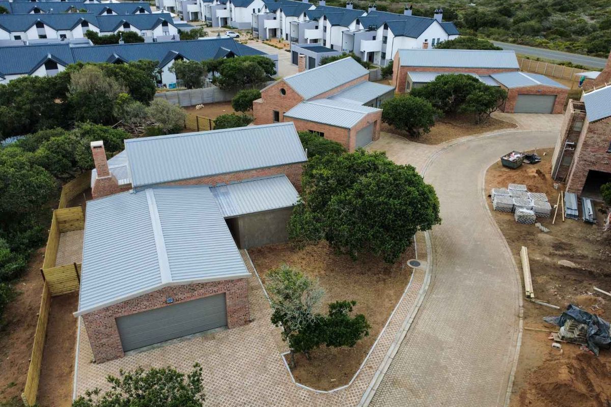 Aerial view of a modern brick townhouse complex featuring metal roofing, paved driveways, and integrated garages within a landscaped estate setting.
