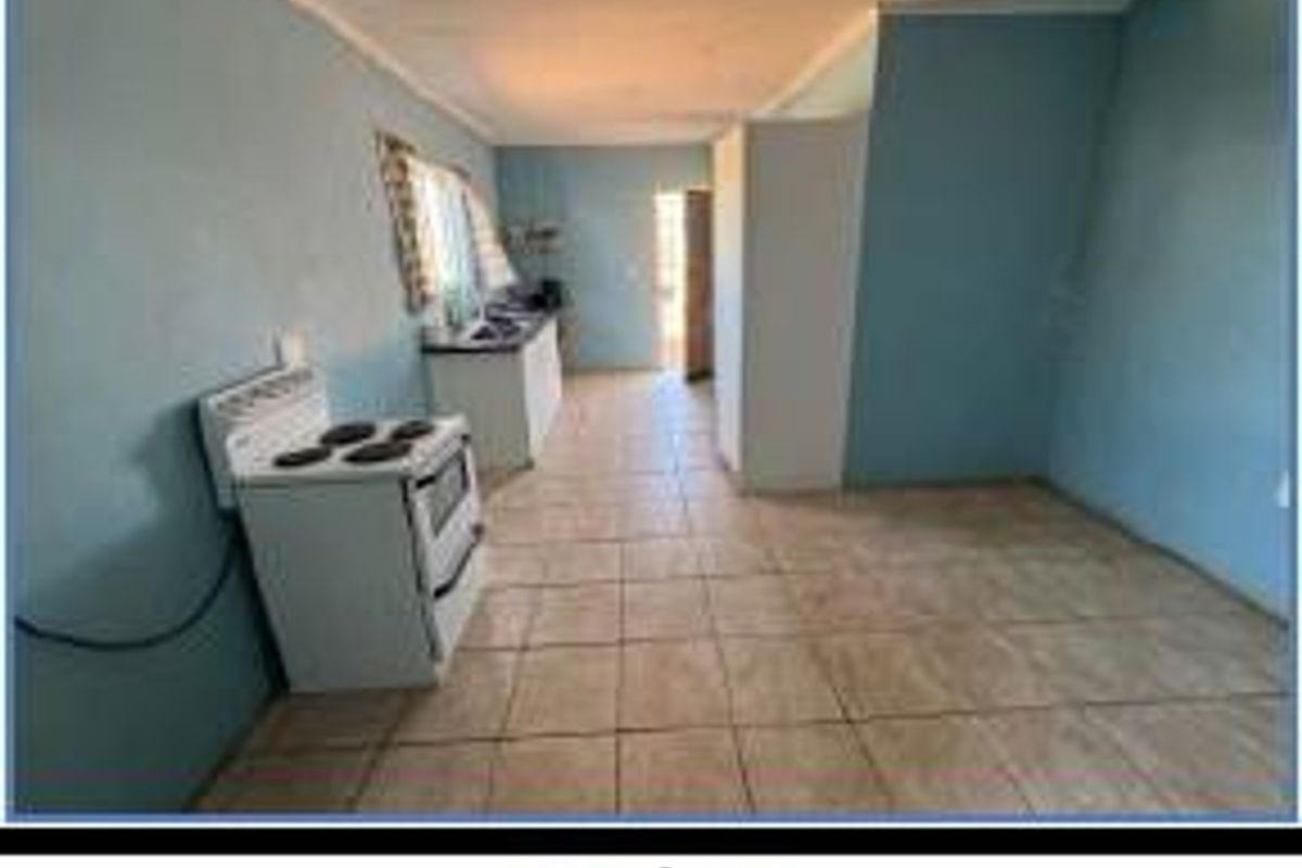 A functional kitchen area featuring tiled flooring, a freestanding stove, and basic cabinetry, offering a blank canvas for potential renovation and modernization.