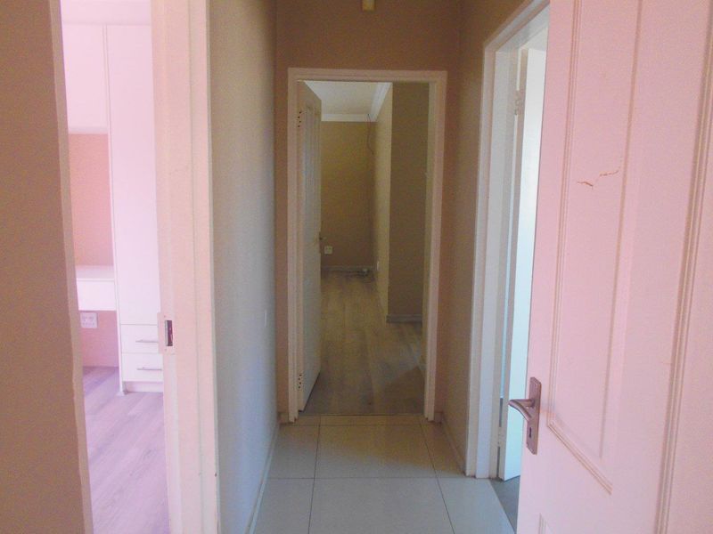 A functional hallway connecting multiple rooms, featuring tiled and laminate flooring with standard internal door access.