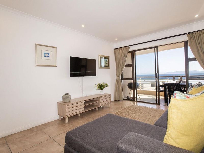 Bright living room featuring tiled flooring and large sliding glass doors that open onto a balcony with ocean views.