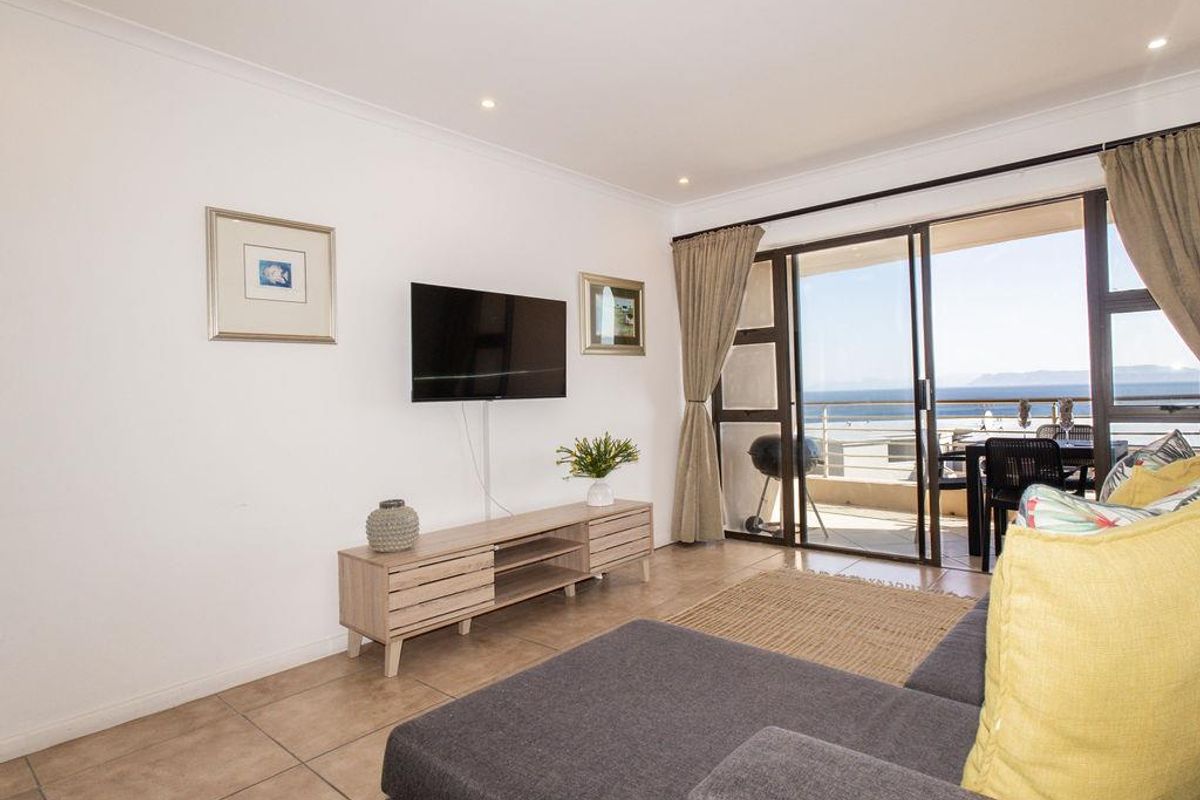Bright living room featuring tiled flooring and large sliding glass doors that open onto a balcony with ocean views.