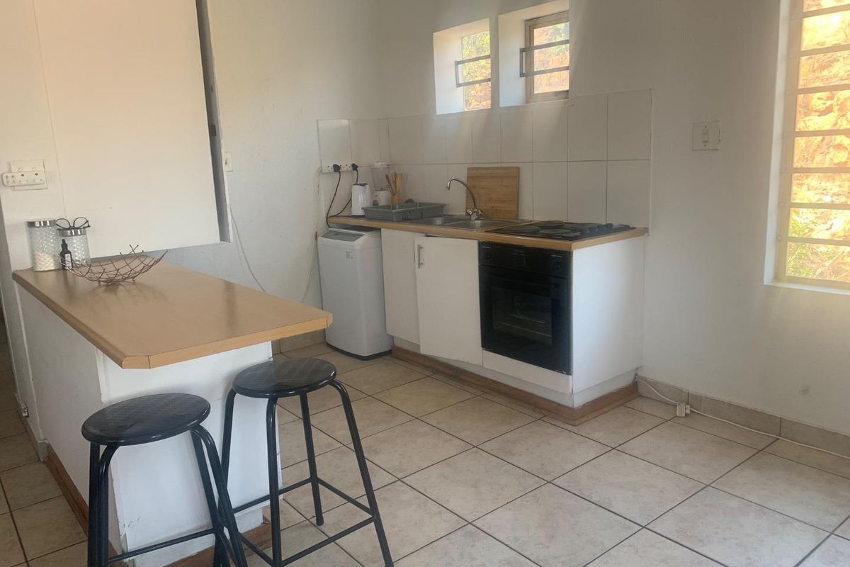 Compact kitchen featuring built-in cabinetry, integrated oven and hob, tiled flooring, and a breakfast bar counter.