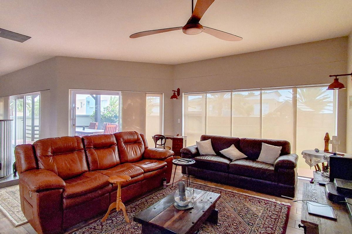 Spacious living room featuring a wood-burning fireplace, ceiling fan, and large sliding glass doors that provide ample natural light.