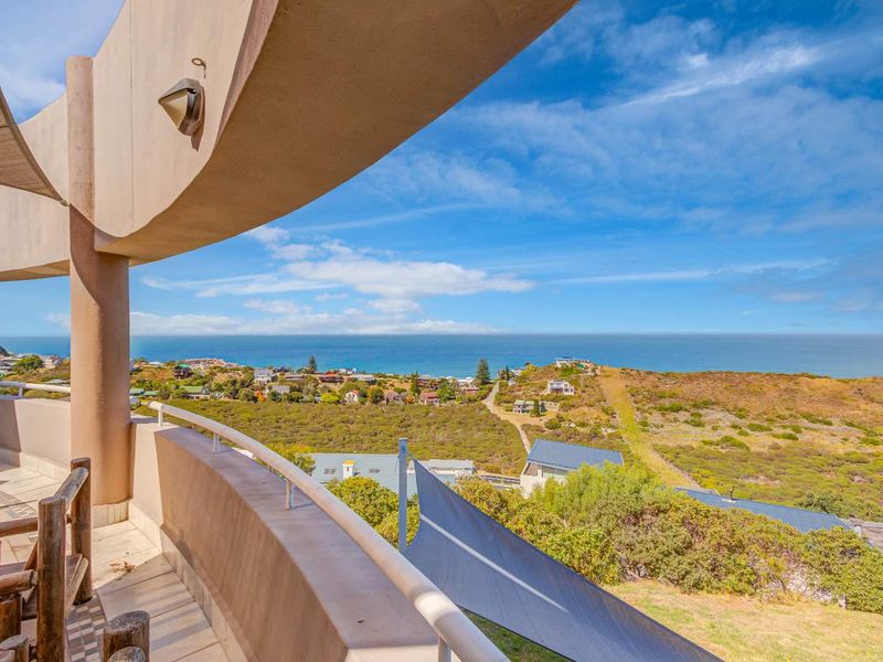 Spacious curved balcony featuring tiled flooring and metal railings, offering expansive panoramic views of the coastline and surrounding landscape.