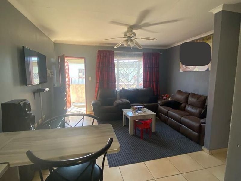 Open plan living area featuring tiled flooring, a ceiling fan, and a breakfast bar, with direct access to an exterior entrance.