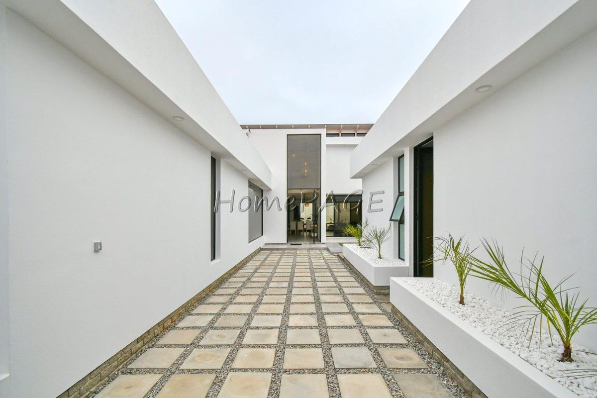 A modern, clean-lined exterior walkway featuring paved stone tiles, integrated planter boxes, and recessed lighting leading to the main entrance.