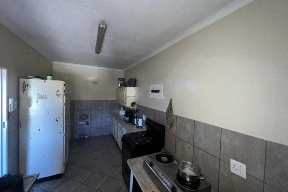 A functional kitchen featuring tiled flooring, tiled splashbacks, and built-in cabinetry, offering a practical layout in need of cosmetic updates.