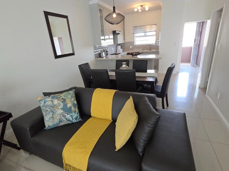 An open-plan living and dining area featuring tiled floors, modern kitchen cabinetry, and integrated lighting, creating a bright and functional living space.