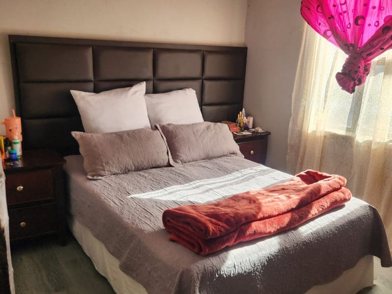 A bedroom featuring laminate flooring and a coved ceiling, currently requiring cosmetic updates to the wall and ceiling finishes.