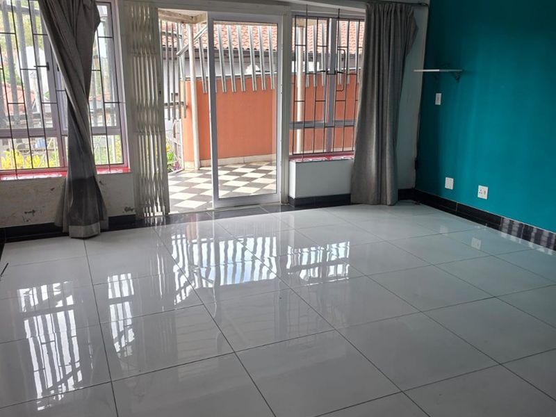 Spacious living area featuring polished porcelain floor tiles, recessed lighting, and direct access to an outdoor patio through sliding glass doors.