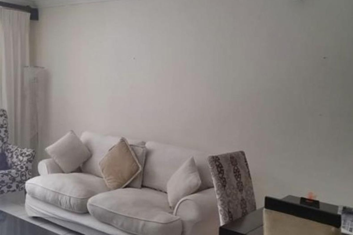 A living room area featuring tiled flooring and a panelled ceiling, providing a functional space for relaxation.