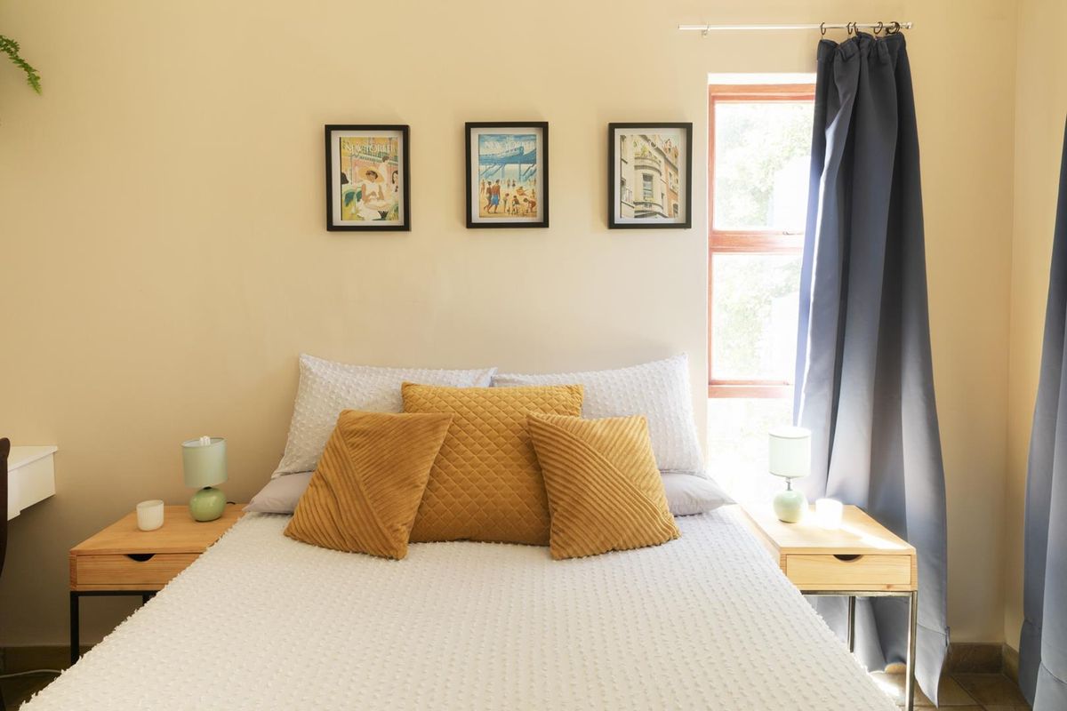 A well-lit bedroom featuring neutral wall tones, a window with curtains, and a comfortable sleeping area.