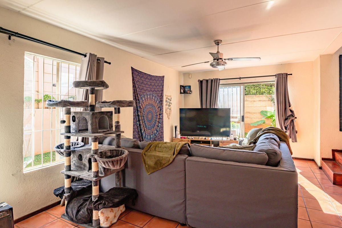 A living room featuring tiled flooring, a ceiling fan, and sliding glass doors providing access to the outdoor area.