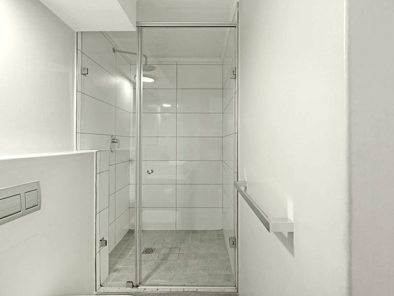 Modern bathroom featuring a walk-in shower with glass enclosure, white wall tiling, and a concealed cistern toilet.