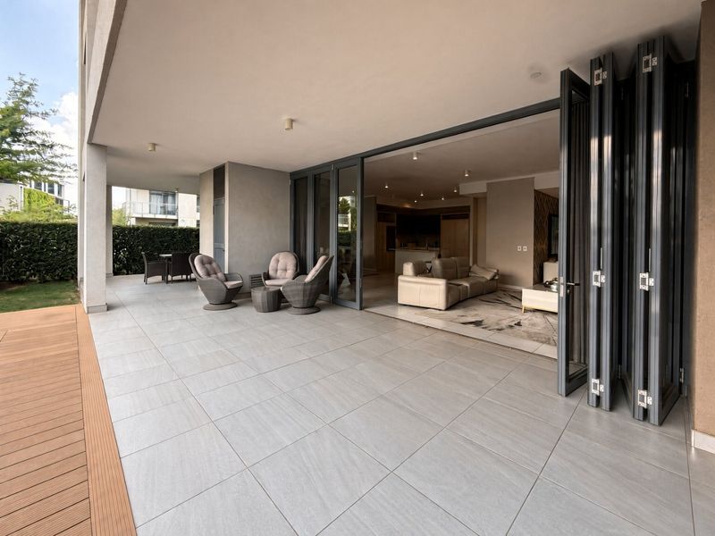 Spacious covered patio featuring large-format floor tiles, timber decking, and seamless indoor-outdoor flow through modern stacking glass doors.