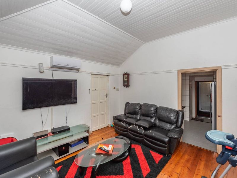 Living room featuring timber flooring and a vaulted ceiling, equipped with a wall-mounted split-system air conditioner.