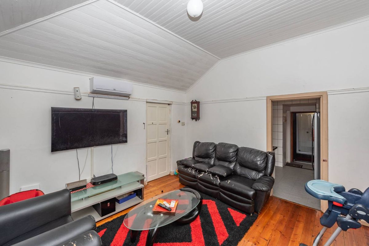 Living room featuring timber flooring and a vaulted ceiling, equipped with a wall-mounted split-system air conditioner.