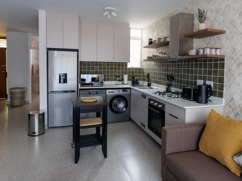 Modern open-plan kitchen featuring sleek cabinetry, stone countertops, a gas hob, built-in oven, and stylish tiled backsplash, seamlessly integrated into the living space.